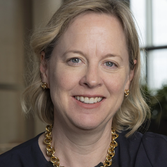 Image of blond woman smiling in front of a window