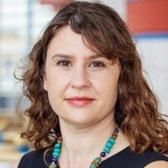 Woman with long brown hair wearing a black dress and necklace