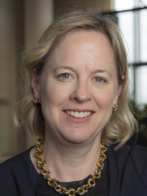 Image of blond woman smiling in front of a window