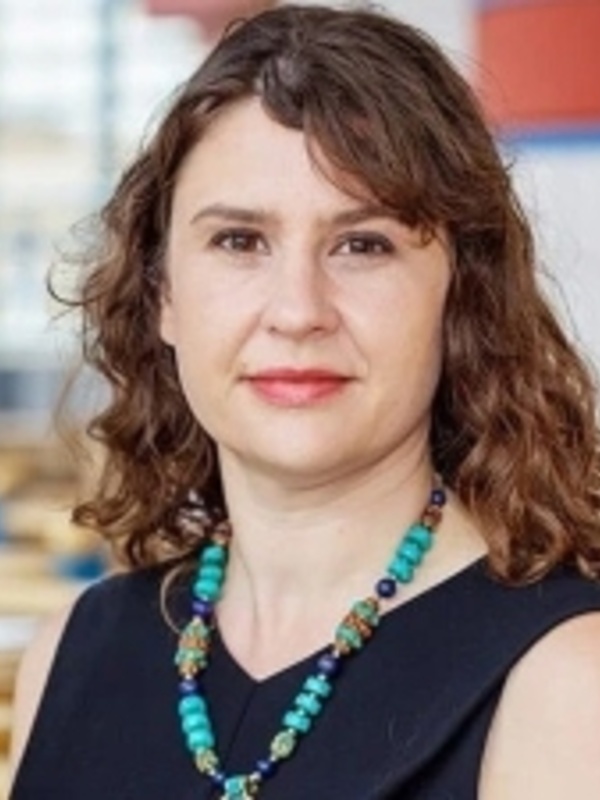 Woman with long brown hair wearing a black dress and necklace