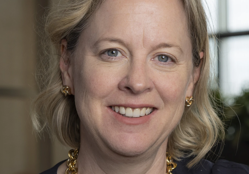 Image of blond woman smiling in front of a window
